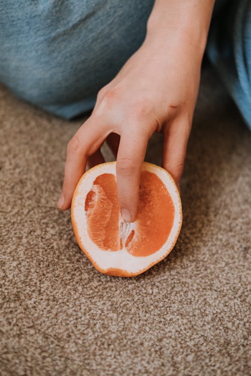 Free Person putting finger in half of exotic grapefruit Stock Photo