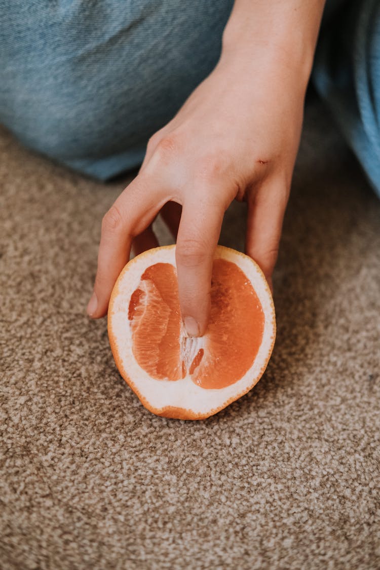 Person Putting Finger In Half Of Exotic Grapefruit