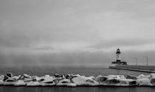 Grayscale Photo of Rocky Shore With Lighthouse