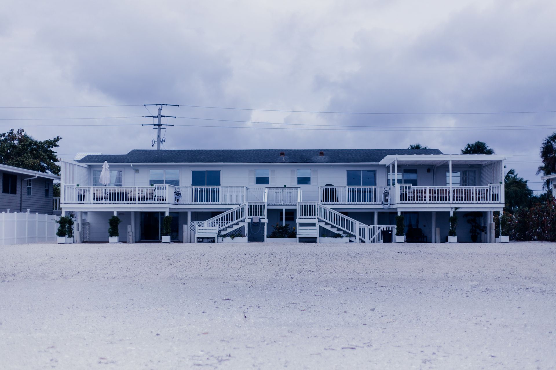 A contemporary beach house with a large deck, captured on an overcast day, highlighting modern architecture.