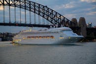 黄昏时分，一艘优雅的游轮正航行在悉尼标志性的海港大桥下