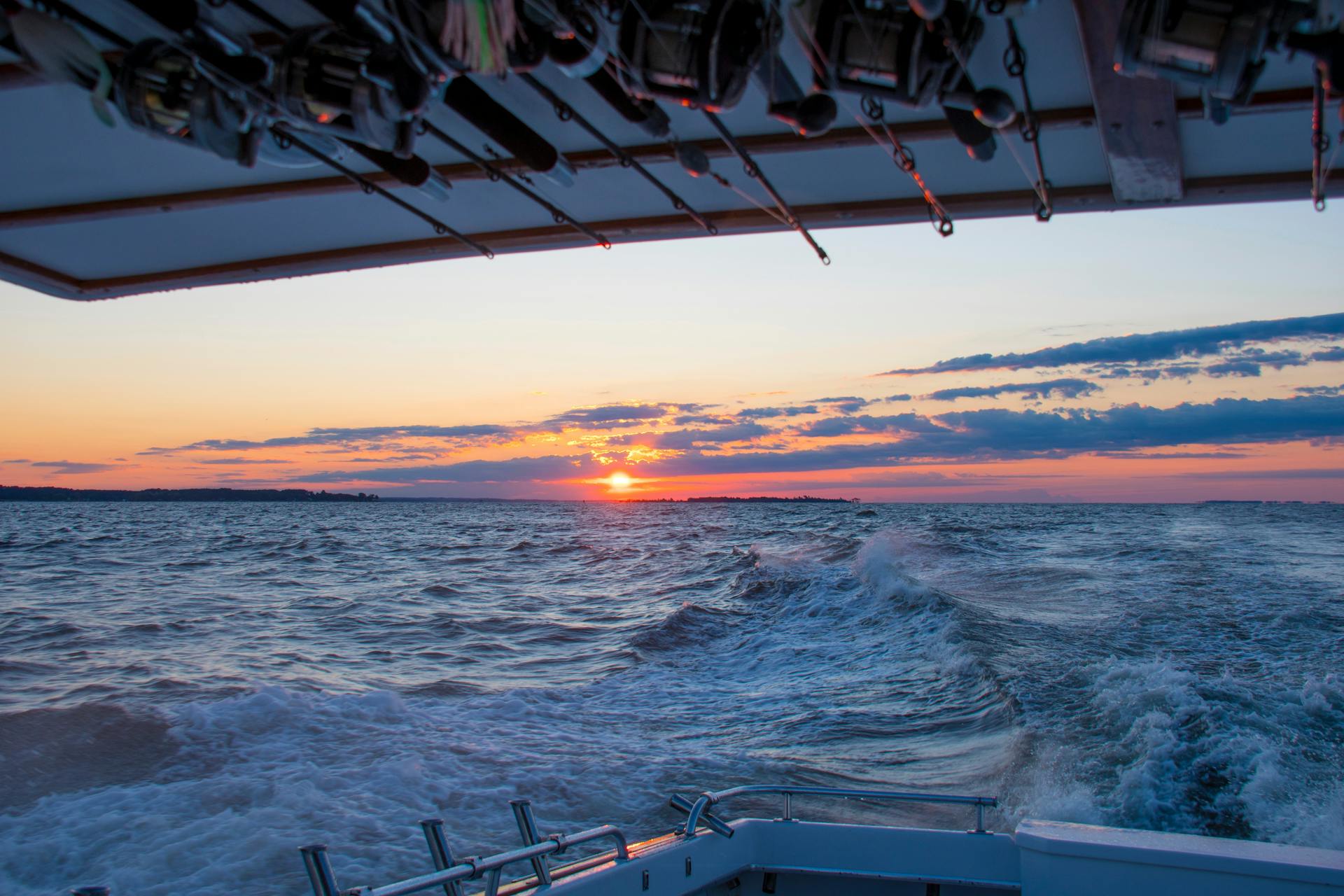 Stunning sunset view from a fishing boat over the ocean waves, perfect for travel and nature themes.