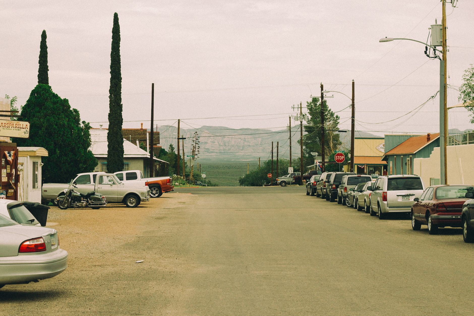 A peaceful outdoor scene featuring parked vehicles, trees, and distant mountains.