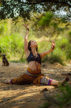 Full body of slim female doing split and looking up while exercising hanumanasana asana during yoga practice in summer nature
