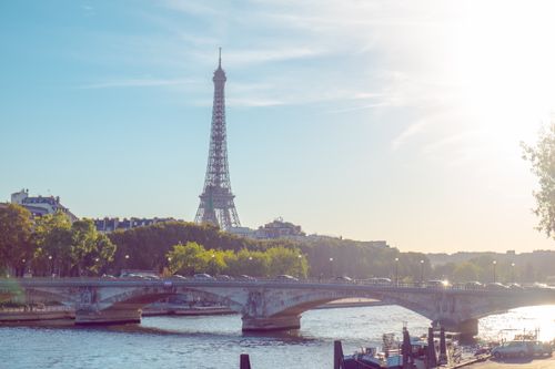 Free A sunny day in Paris featuring the Eiffel Tower and a bridge over the Seine River. Stock Photo