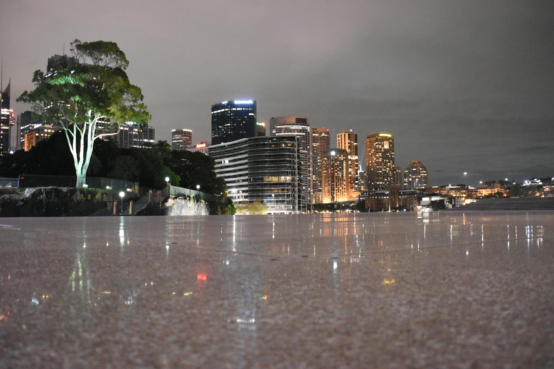 Stunning nighttime view of Sydney's illuminated skyline reflected on a waterfront surface.