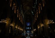 这座光线昏暗的哥特式大教堂内部，展示了美丽的拱门、柱子和彩色玻璃窗