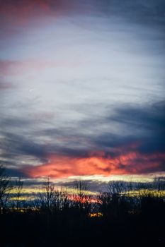 Dark thick clouds floating on bright sky over grassy meadow at sundown time in rural terrain in nature in evening