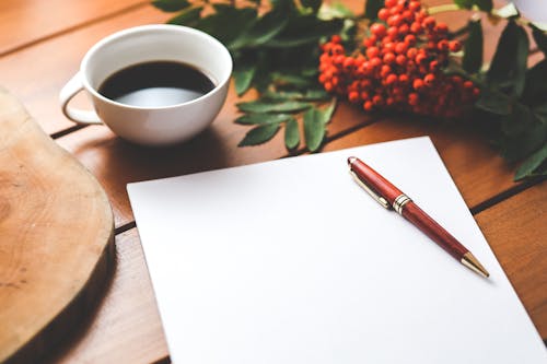 Free Blank paper with pen and coffee cup on wood table Stock Photo