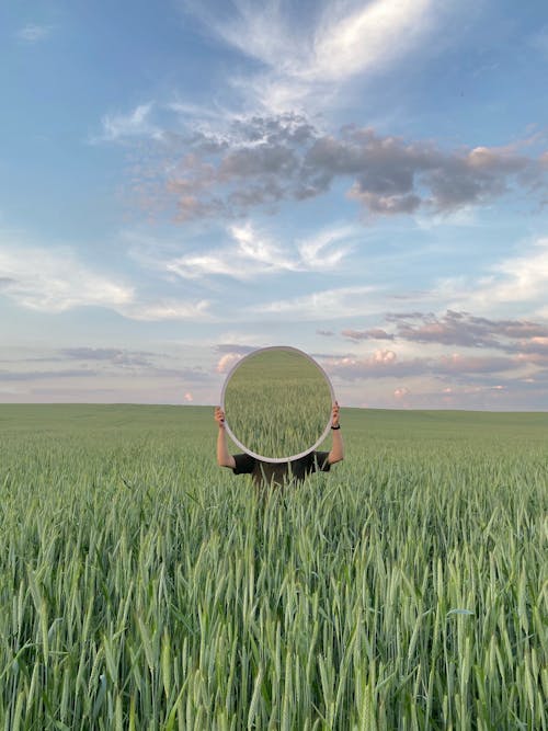 Anonymous person in green grass with mirror