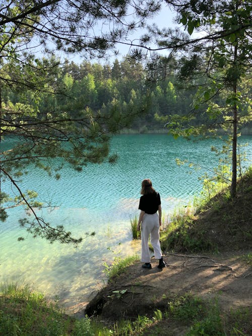 Unrecognizable woman walking near lake in forest