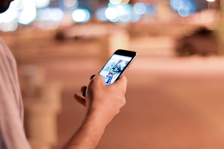 Man Holding And Scrolling A Black Smartphone