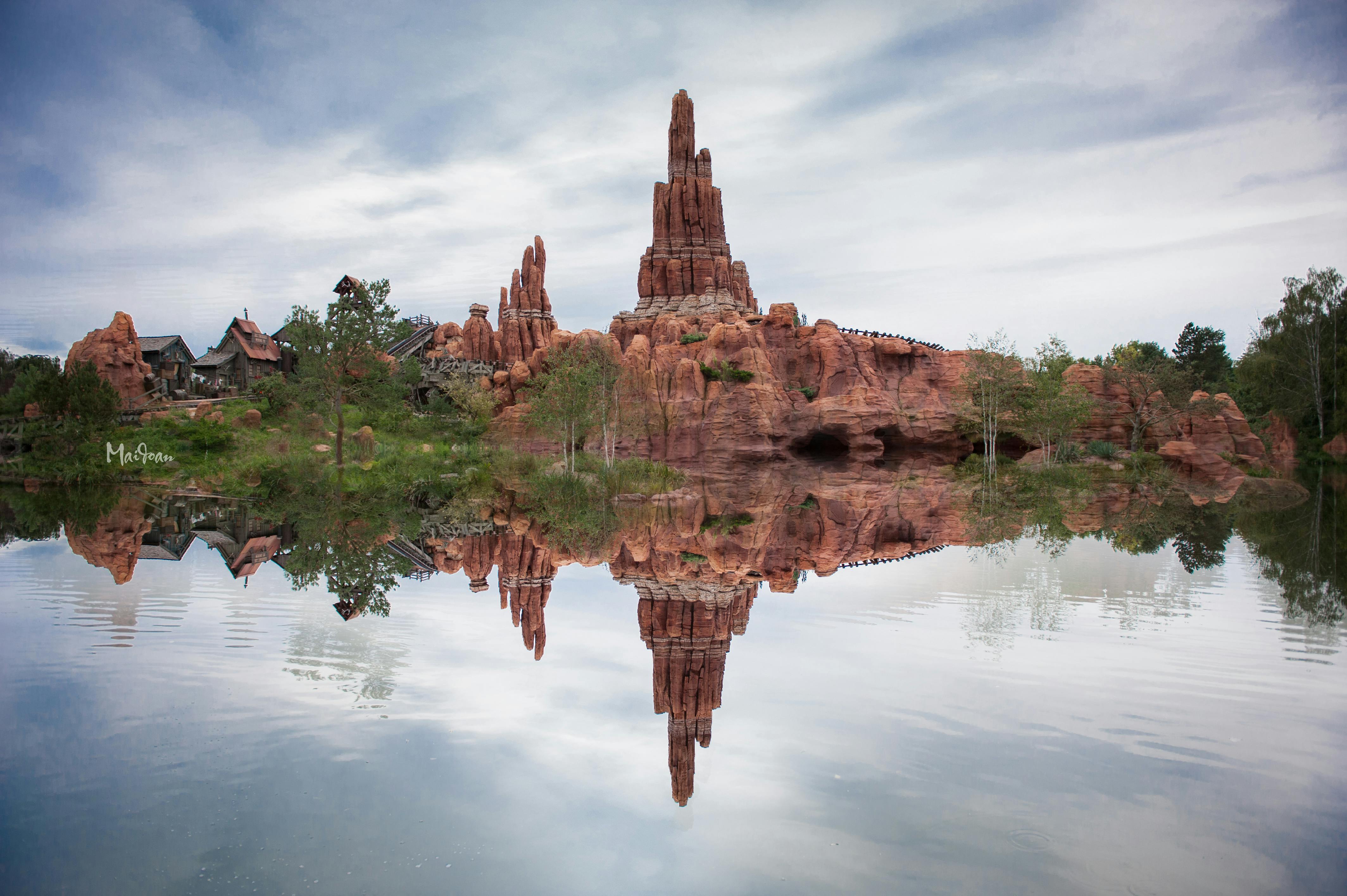 Majestic rock formation reflected in calm water under a serene sky, perfect for nature and travel enthusiasts.