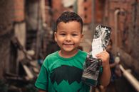 Happy ethnic little kid with new plastic toy car in casual outfit looking at camera