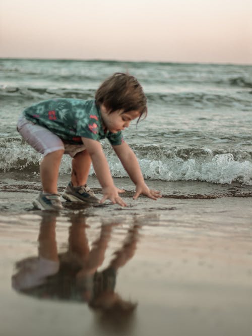 A Boy Wearing Casual Clothing and Sneakers Playing on the Seashore
