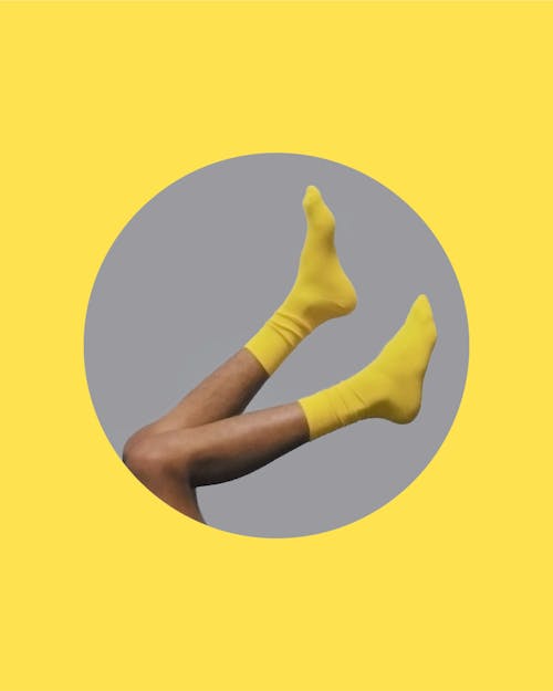 Side view of crop unrecognizable person in yellow socks in circle on gray background