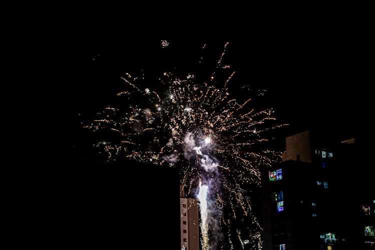 Glowing Firework Exploding Above Tall Building