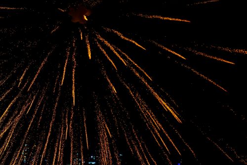 Free From below of bright golden fireworks exploding in dark sky during festive event celebration on street at night time in city Stock Photo