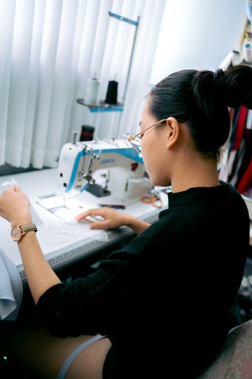 A Woman in Black Long Sleeves Sitting Near the Table with Sewing Machine