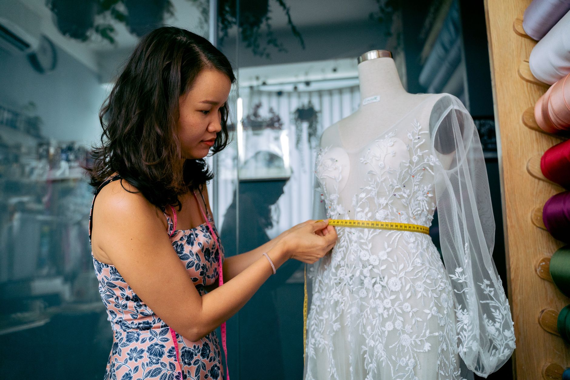 A seamstress measuring a gown on a mannequin mirrors the labour hidden inside last-minute bridal alterations
