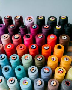 A vibrant collection of sewing threads displayed alongside fabric swatches in a creative studio.