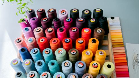 A vibrant collection of sewing threads displayed alongside fabric swatches in a creative studio.