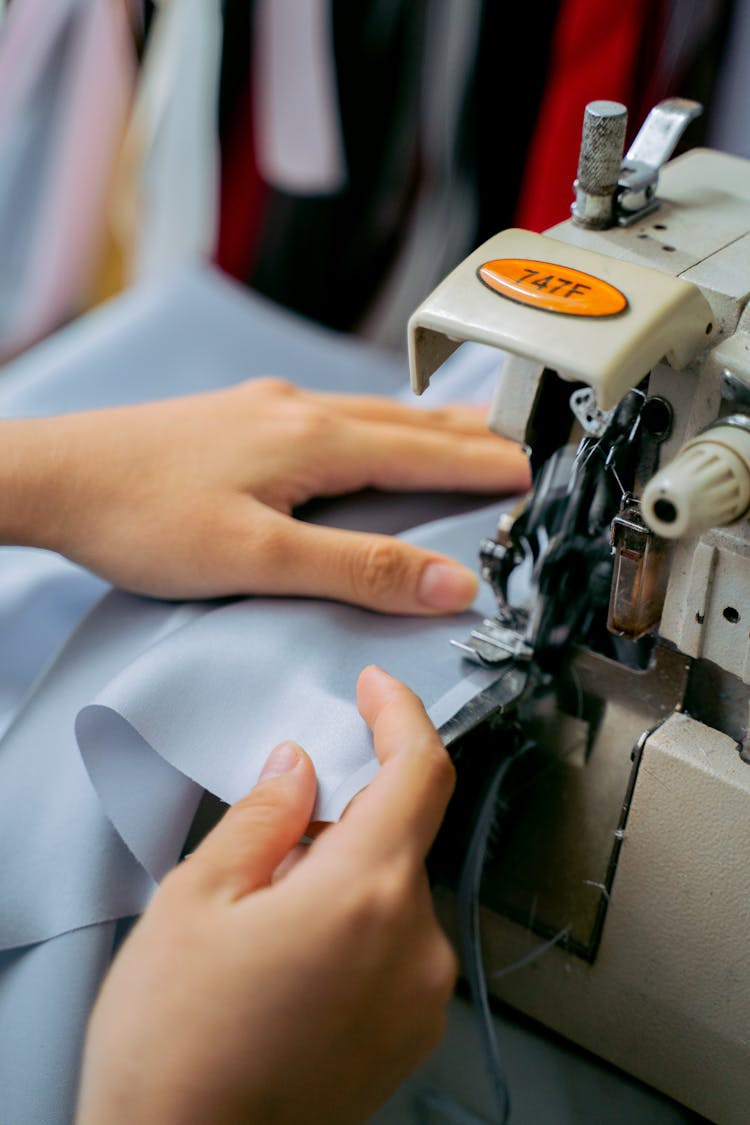 A Person's Hands Using A Sewing Machine