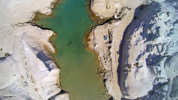 Stunning aerial shot of Sarakiniko Beach in Milos, Greece, showcasing volcanic rock formations and turquoise waters.