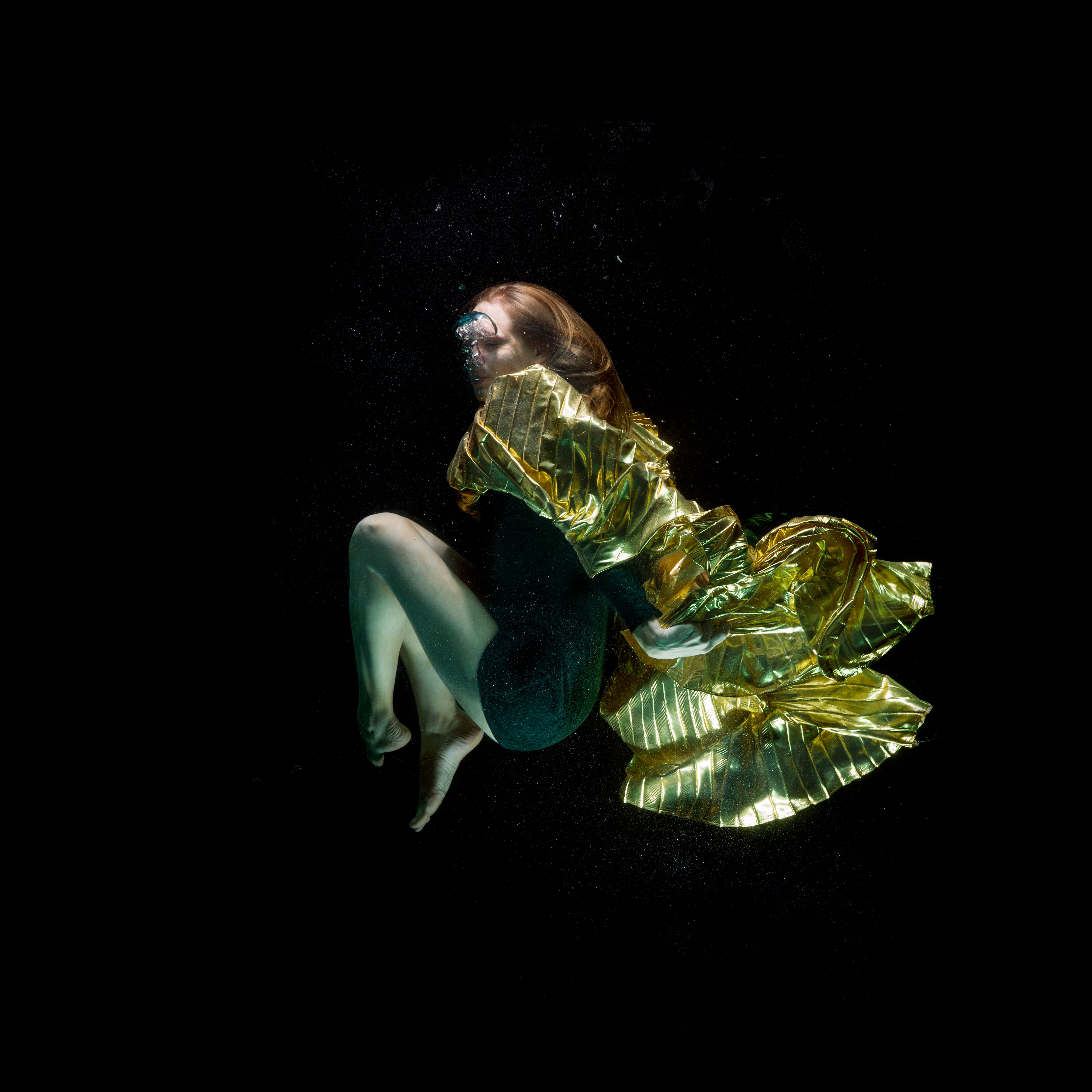 Stunning underwater photography of a woman in a gold dress, creating a dreamy, surreal visual.