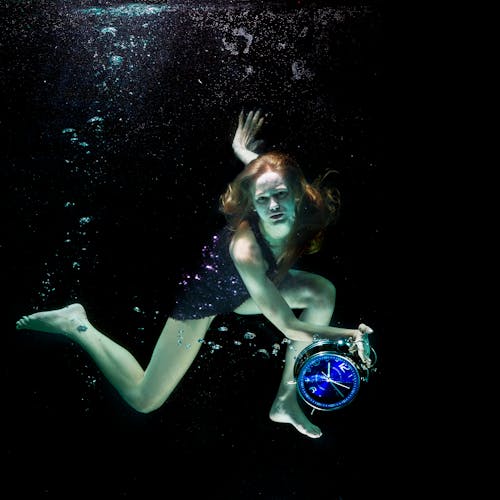 A Woman Holding a Clock Underwater