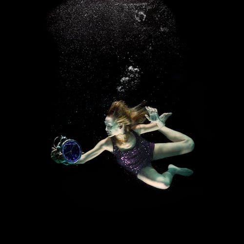 A Woman Holding a Clock Underwater