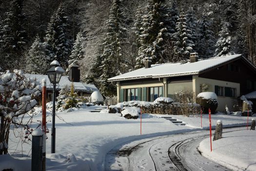 A scenic winter landscape featuring a snow-covered house nestled in a forest environment.