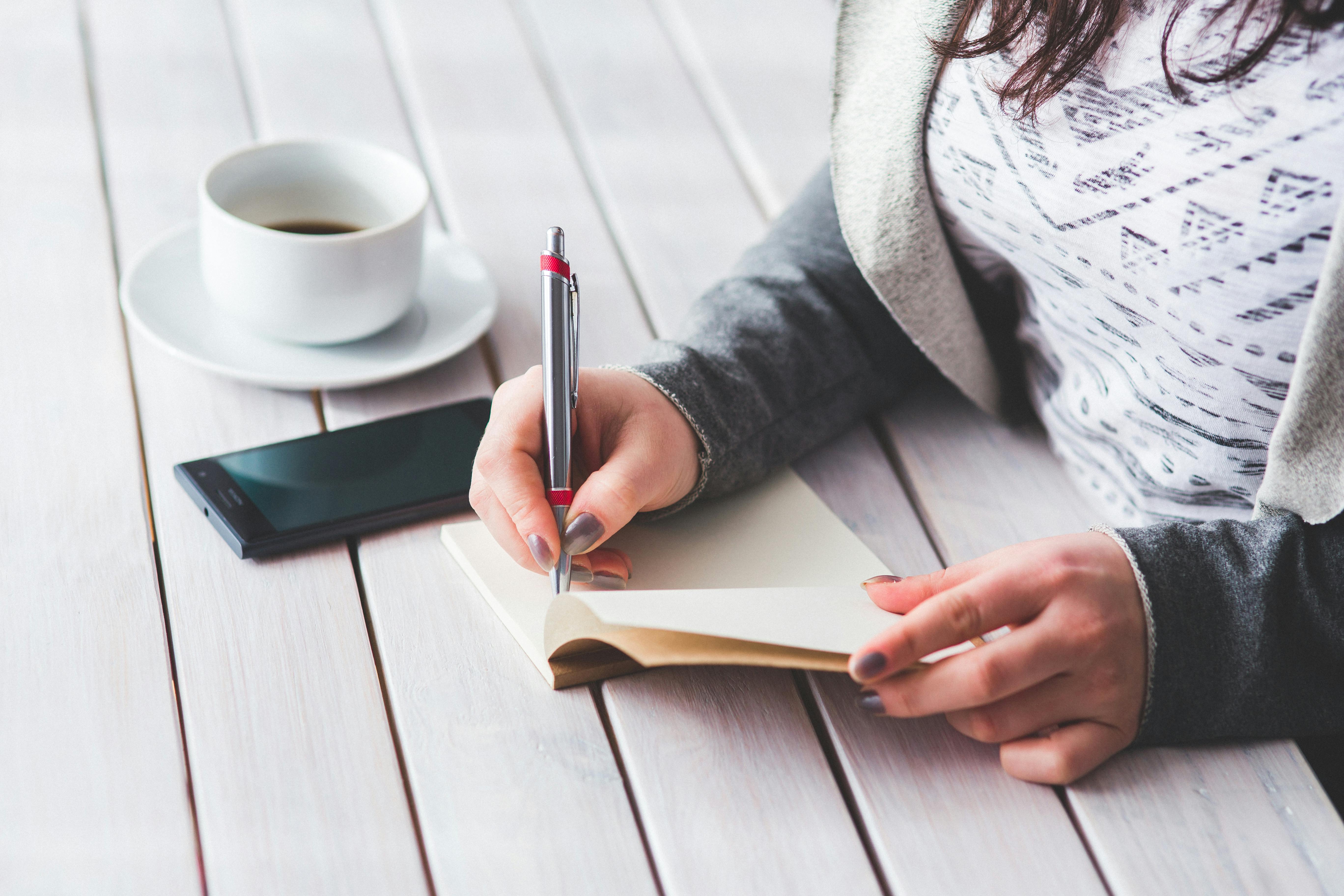 woman s hand using a pen noting on notepad