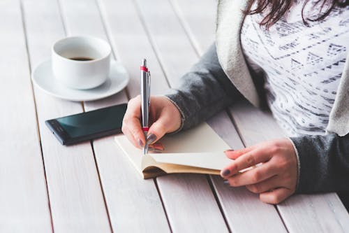 Woman's hand using a pen noting on notepad