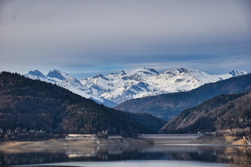 Snowy Mountains and Green Mountains Near a Body of Water