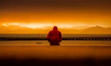 一个穿红色外套的人凝视着旧金山日落充满活力的剪影