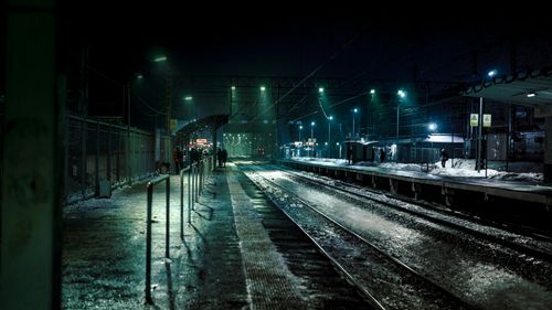 Free Eerie train station platform at night with moody lighting and empty tracks. Stock Photo