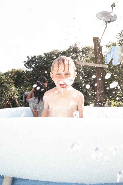 A Shirtless Boy Standing inside a White Inflatable Swimming Pool