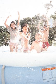 Four children having fun in an outdoor inflatable pool, creating joyful splashes.