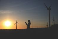 Silhouette Of Woman Holding Book Near Windmills