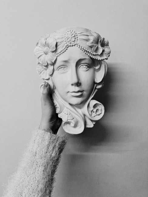 Black and white of crop unrecognizable female in warm clothes demonstrating handicraft plaster sculpture