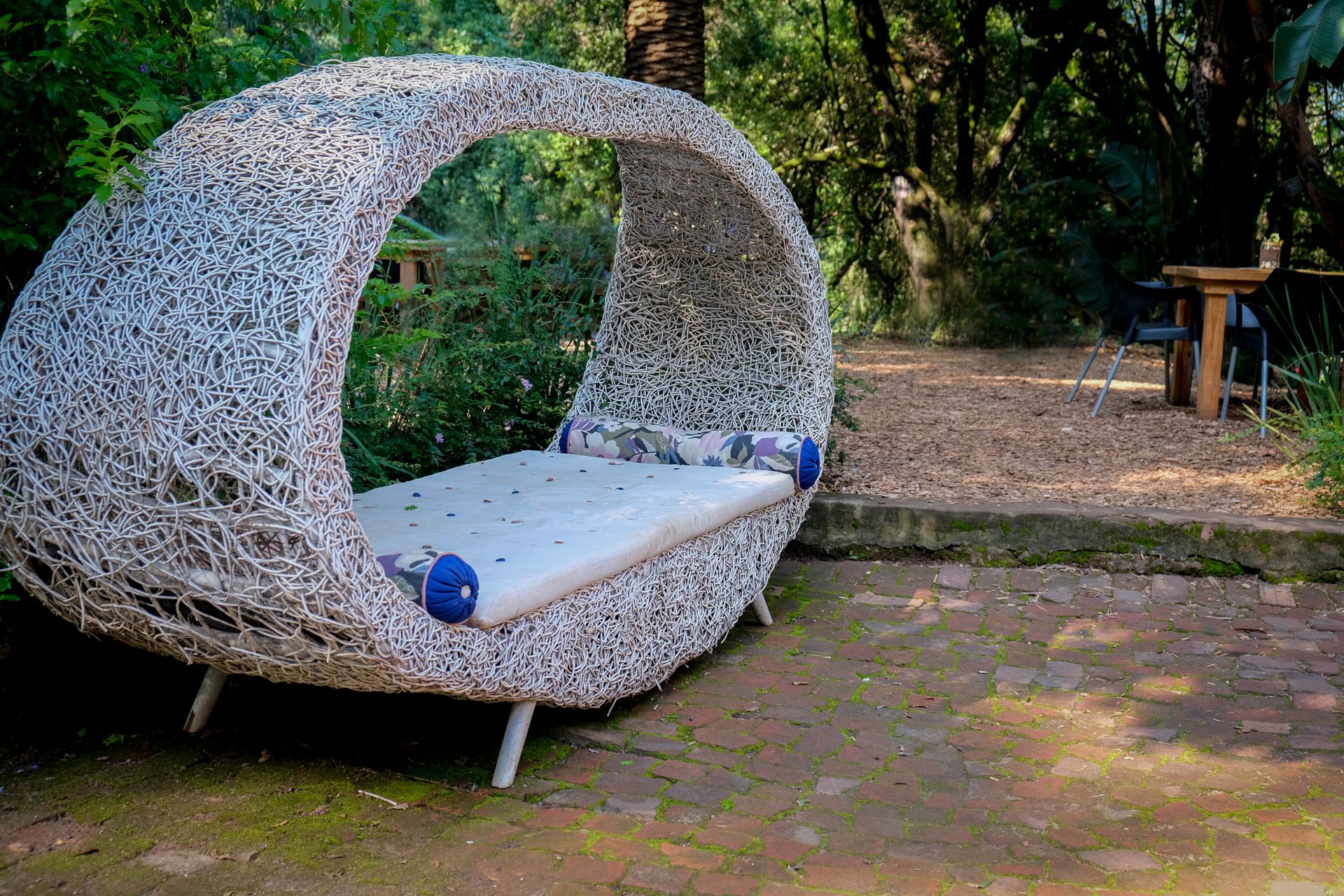 Elegant rattan daybed with comfortable cushions in a serene garden setting, perfect for relaxation.
