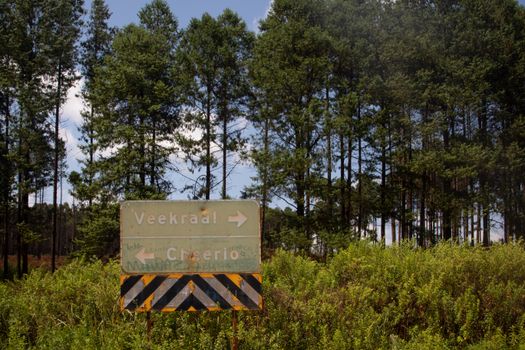 A directional sign in a forest pointing to Veekraal and Cheerio.