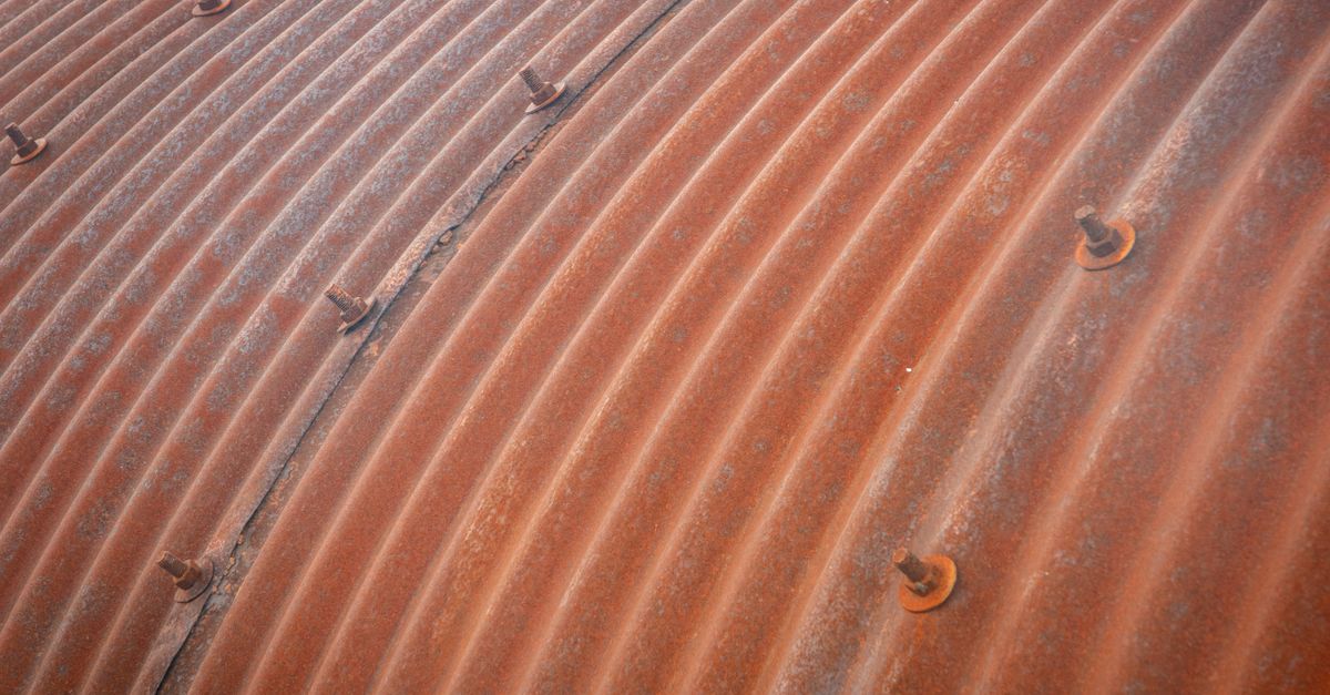 Detailed view of a rusted corrugated metal surface with visible bolts.