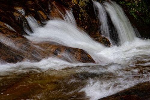 Free Captivating long exposure of water flowing energetically over rocks in a natural setting. Stock Photo