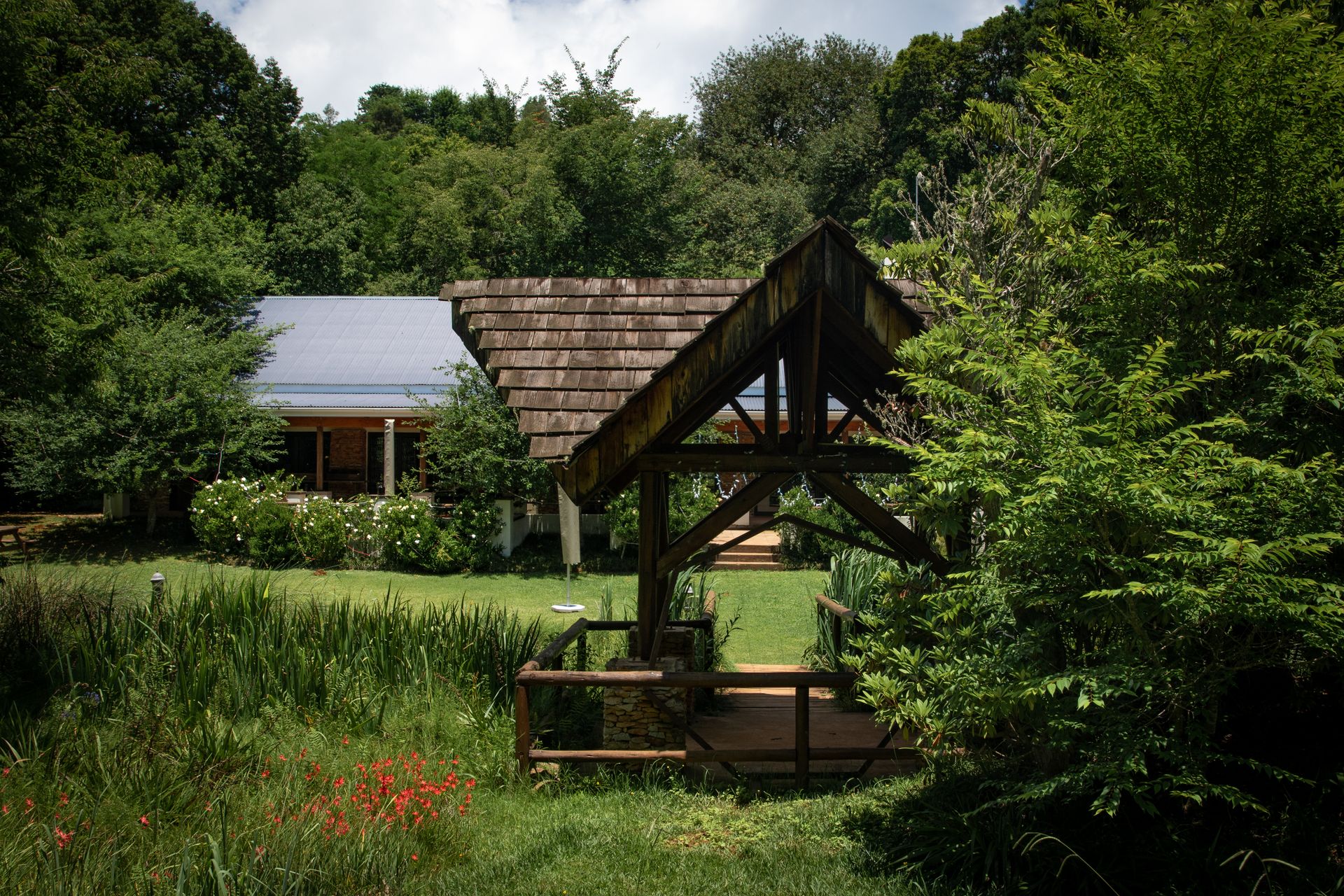A Wooden Gazebo on Green Field Near Green Trres