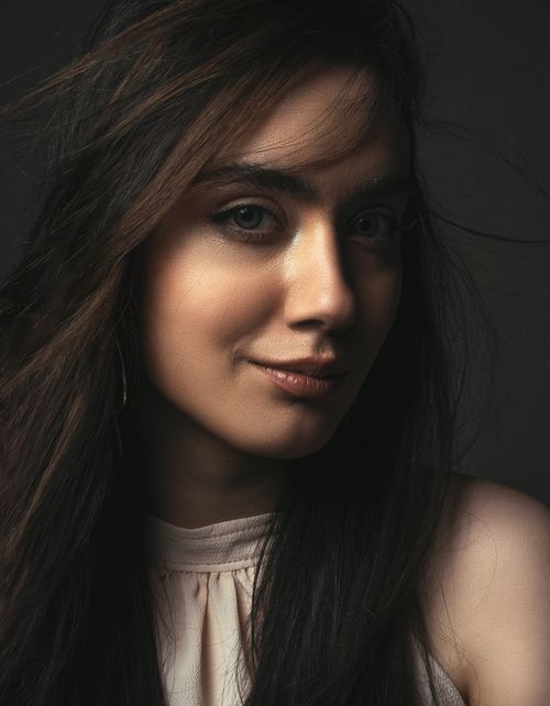 Free Pensive young brunette lady wearing stylish blouse and makeup while looking at camera in light studio Stock Photo