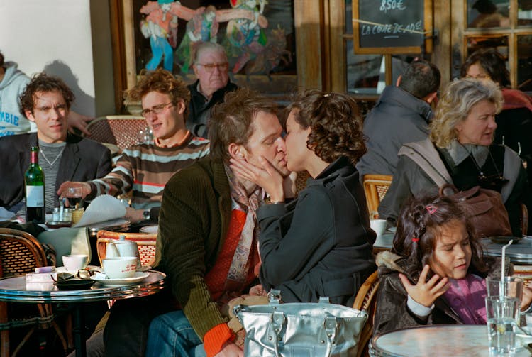 Kissing Couple In Crowded Cafe