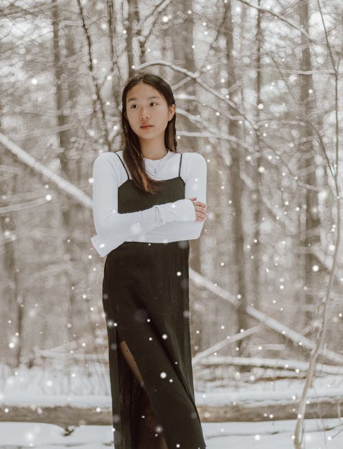Dreamy Asian woman with crossed arms in winter woods