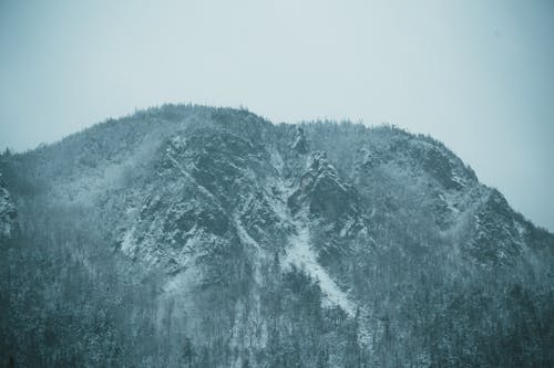 Snowy mountain slope against cloudy sky in daylight